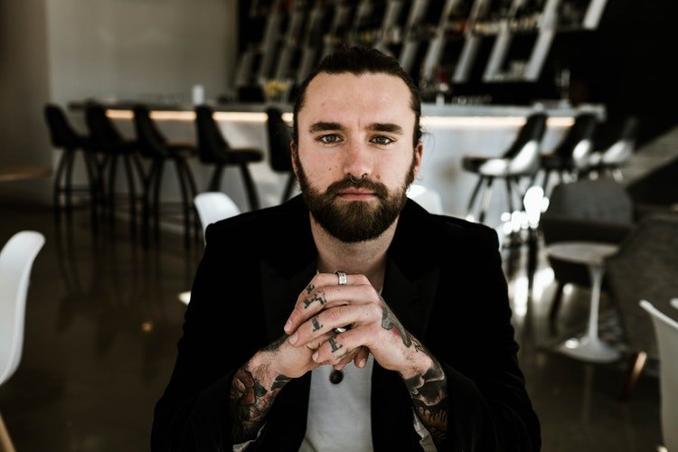 homem sentado em bar com barba